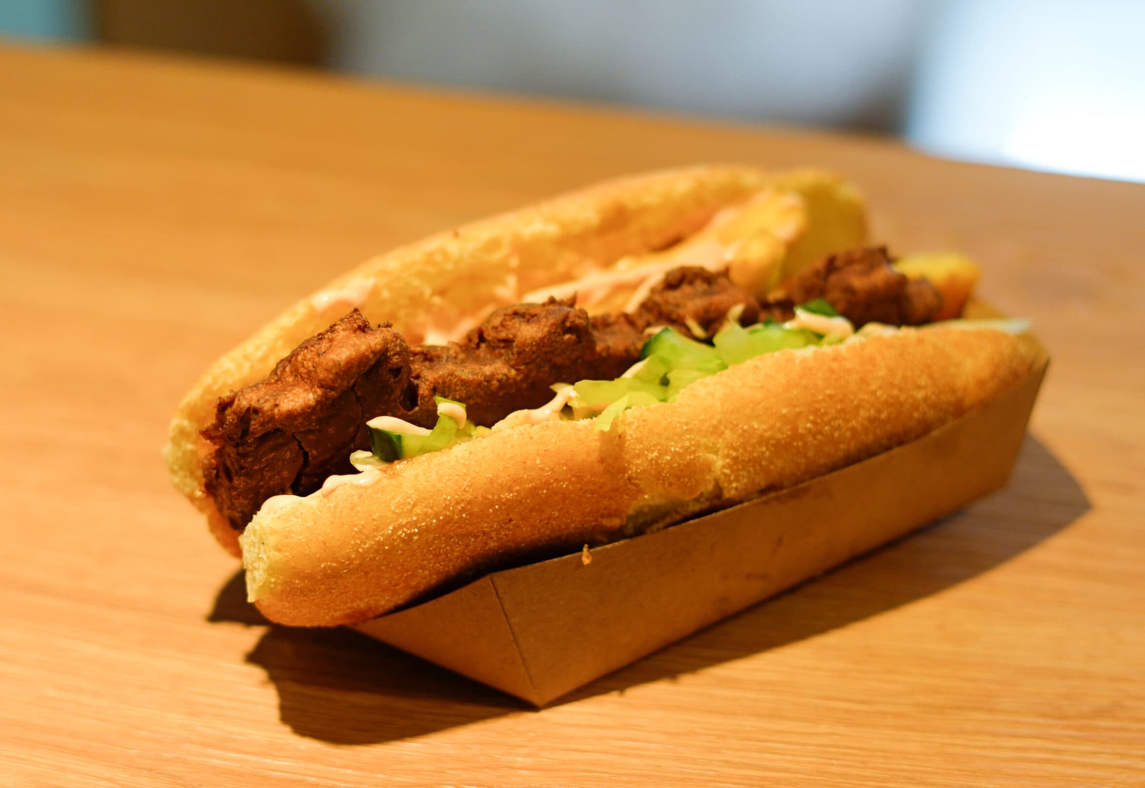 Broodje shoarma met sla en knoflooksaus in een kartonnen bakje.