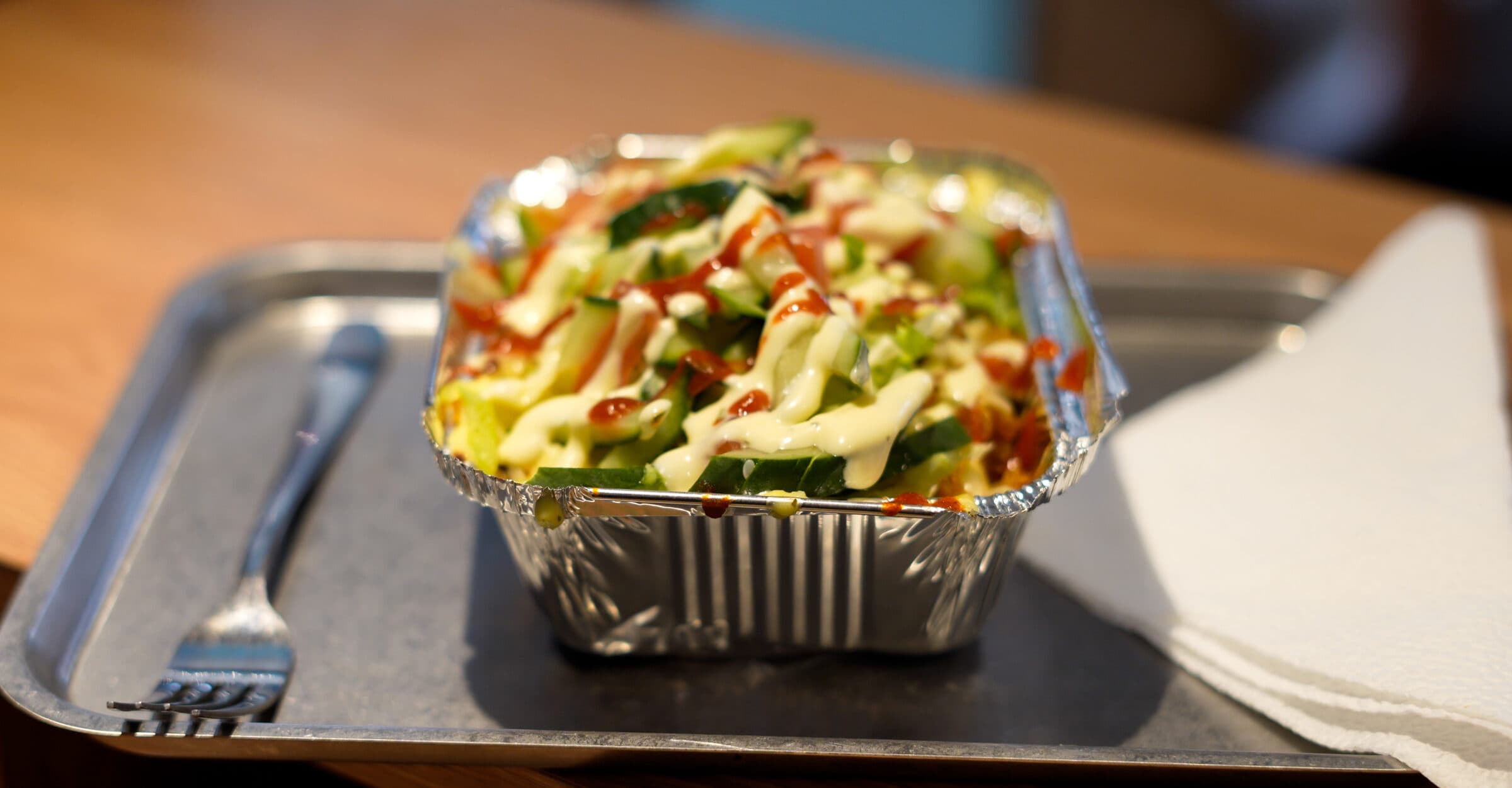 Kapsalon met lams shoarma, gesmolten kaas en knoflooksaus in folie bakje