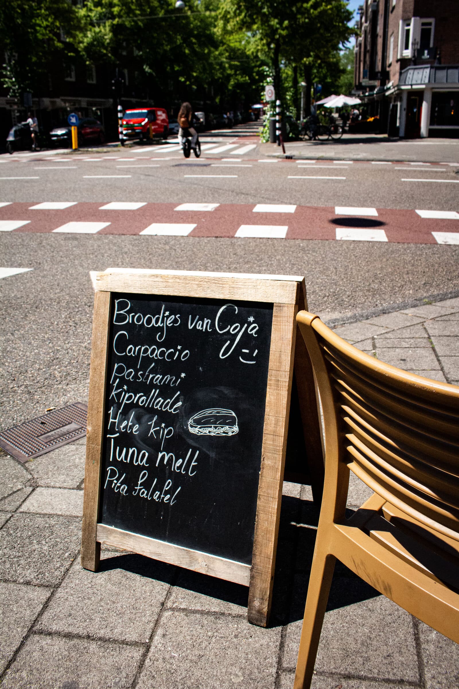 Krijtbord op de stoep met 'Broodjes van Coja' en de lijst carpaccio, pastrami, kiprollade, hete kip, tuna melt en pita falafel.